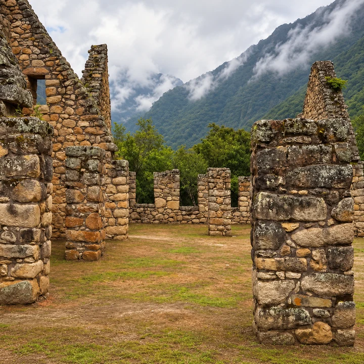 Stone ruins at Chachabamba beneath cloud-covered mountains.
