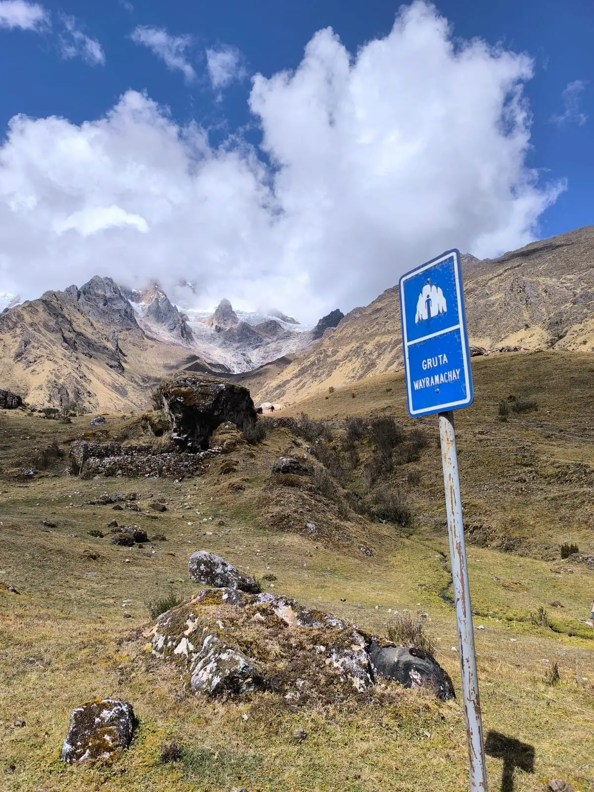 Wayramachay Cave sign with high Andean mountains in the background along the Salkantay route.