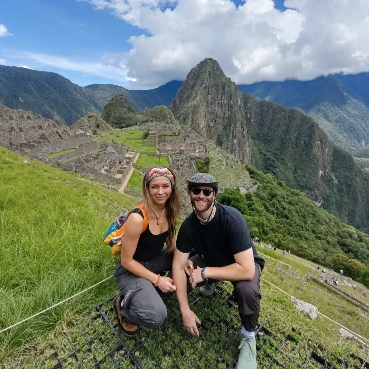 Young couple posing during a full-day tour of Machu Picchu, with the Inca citadel and Huayna Picchu mountain behind them