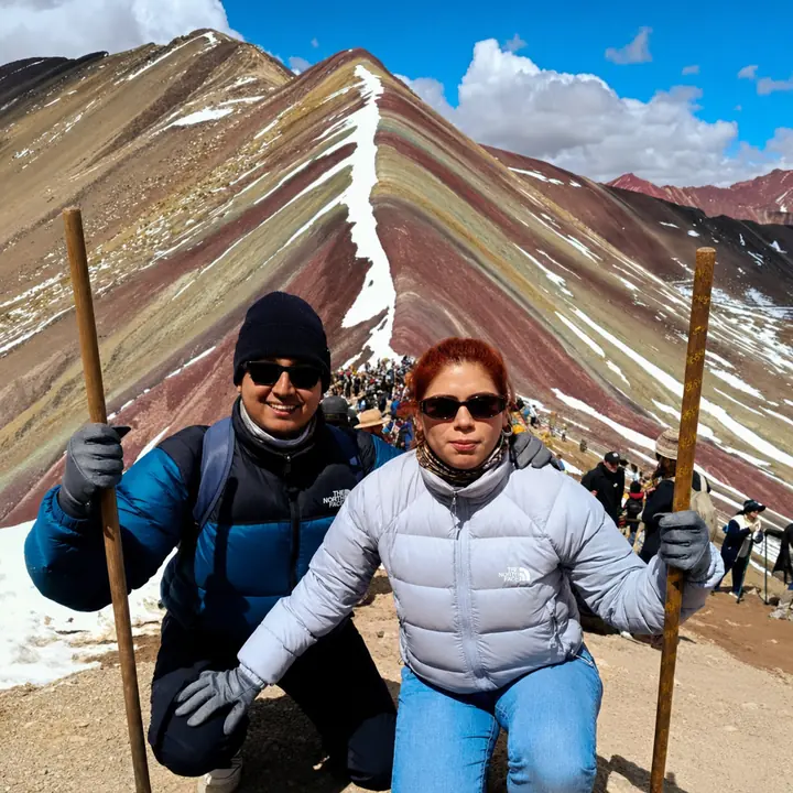 Two hikers holding wooden walking sticks at the Vinicunca summit.