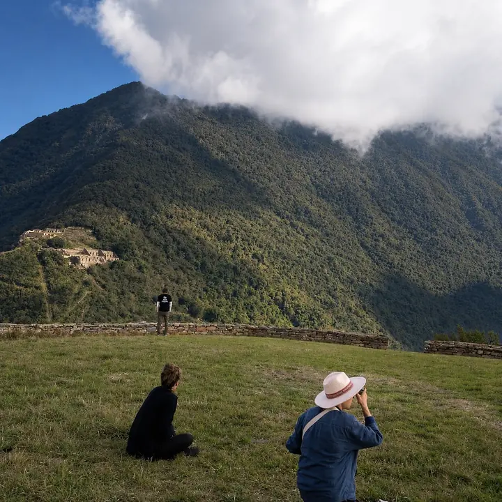 Travelers watching clouds drift above Choquequirao's mountain terraces.