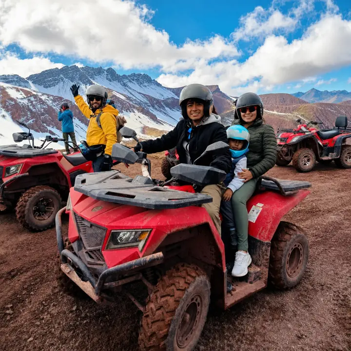 Family wearing helmets on a red ATV in the snowy Red Valley.