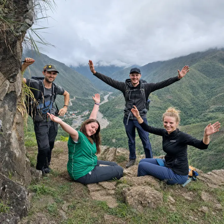Four hikers celebrating above a misty green valley on the Inca Jungle route.