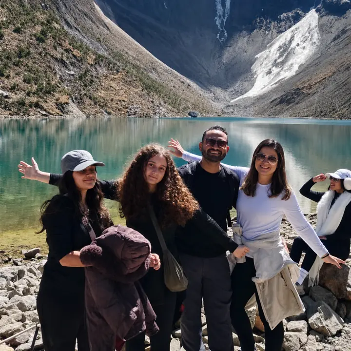 Four travelers posing on the rocky shore of Humantay Lake.