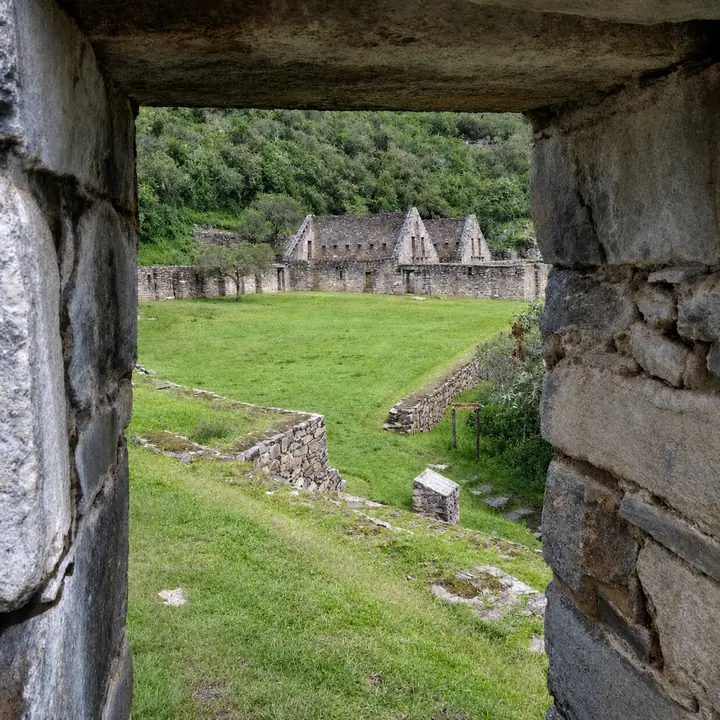 Stone window framing the buildings and terraces of Choquequirao.