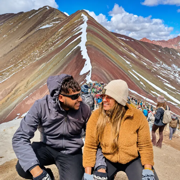 Couple smiling together in front of Rainbow Mountain's colorful ridge.