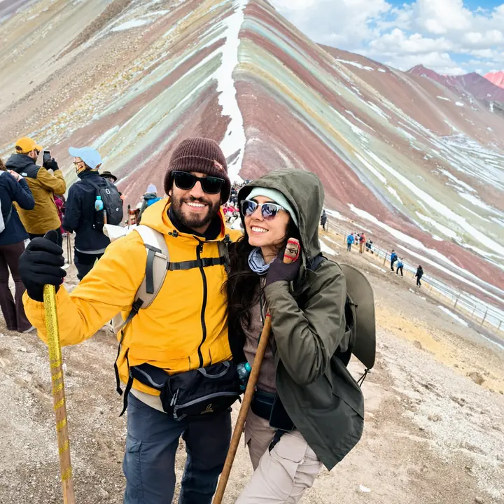 Hiking couple holding walking sticks at the Vinicunca viewpoint.
