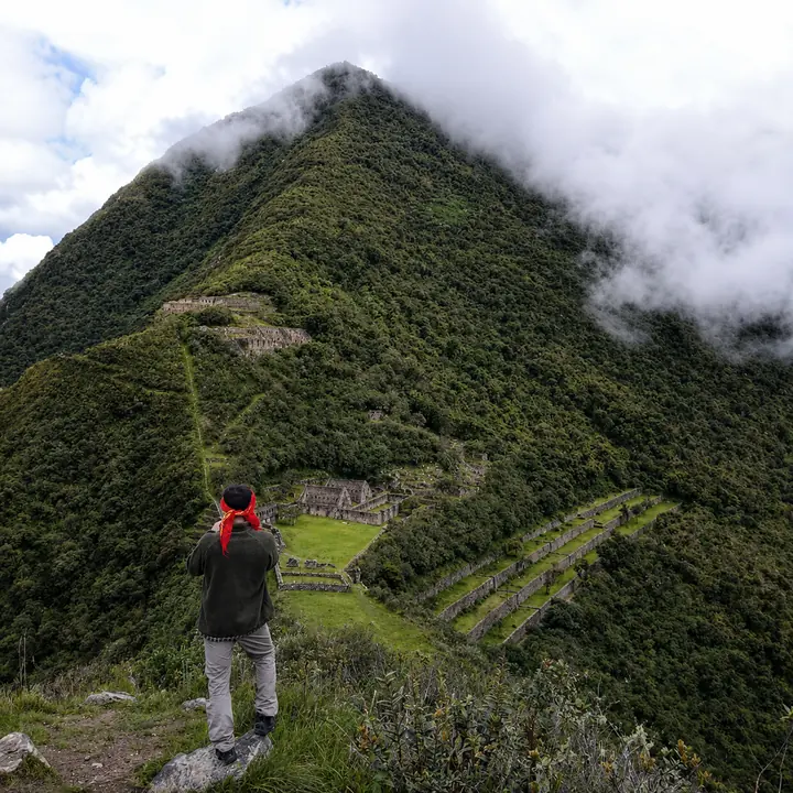Traveler viewing Choquequirao beneath a cloud-covered mountain.