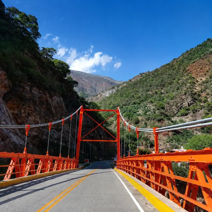 Red suspension bridge crossing a valley on the Choquequirao route.