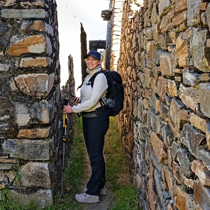 Traveler exploring a narrow stone passage at Choquequirao.