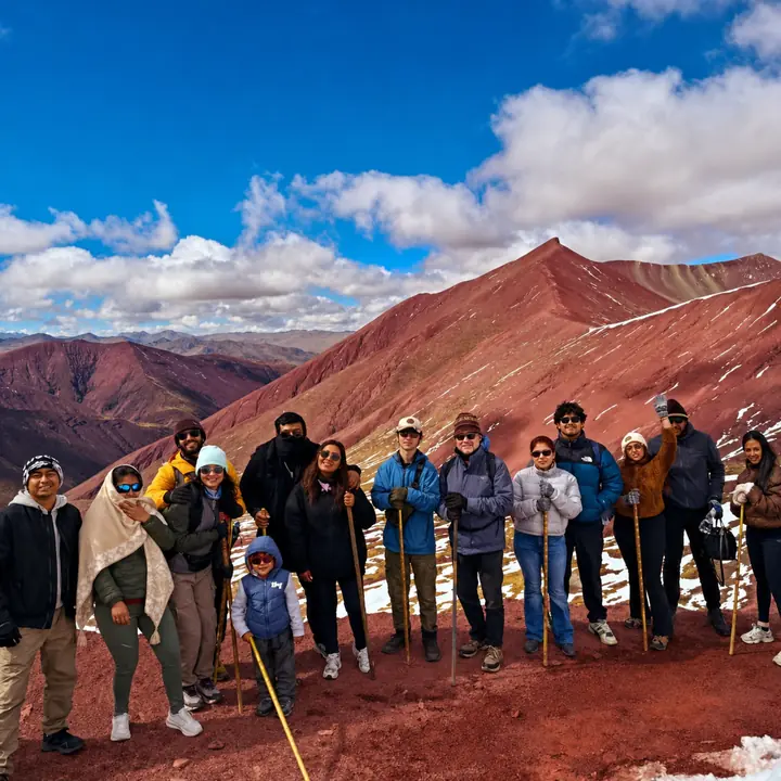 Large tour group posing among the crimson mountains of Peru's Red Valley.