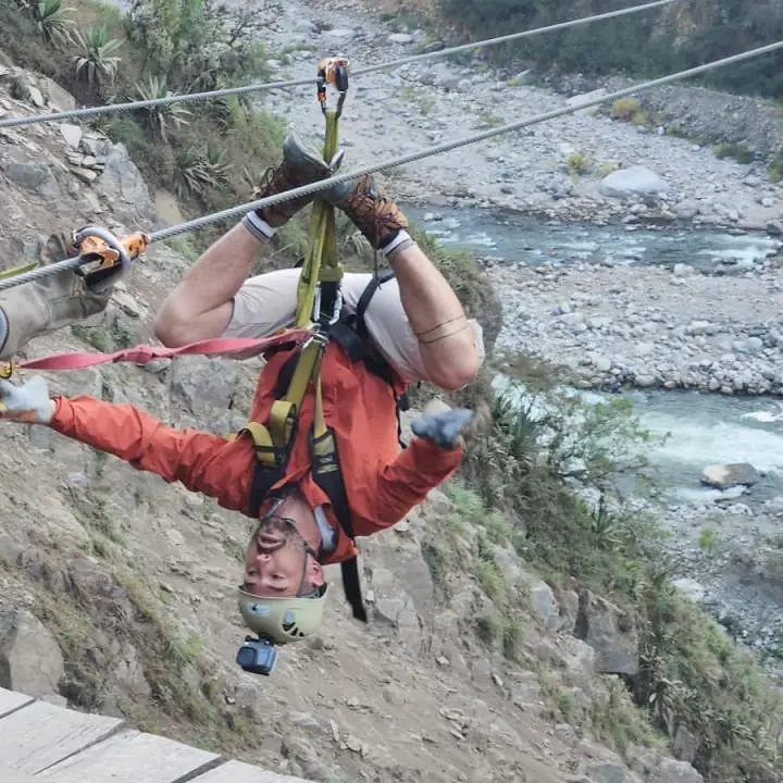 Traveler riding upside down on a zipline above the river valley in Inca Jungle Trail 4 Days.