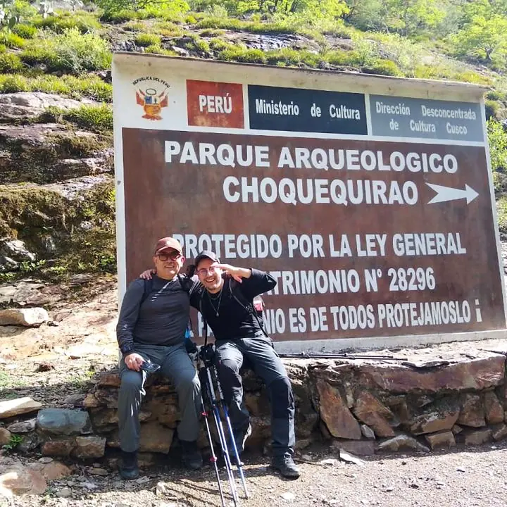 Travelers posing beside the Choquequirao Archaeological Park sign.