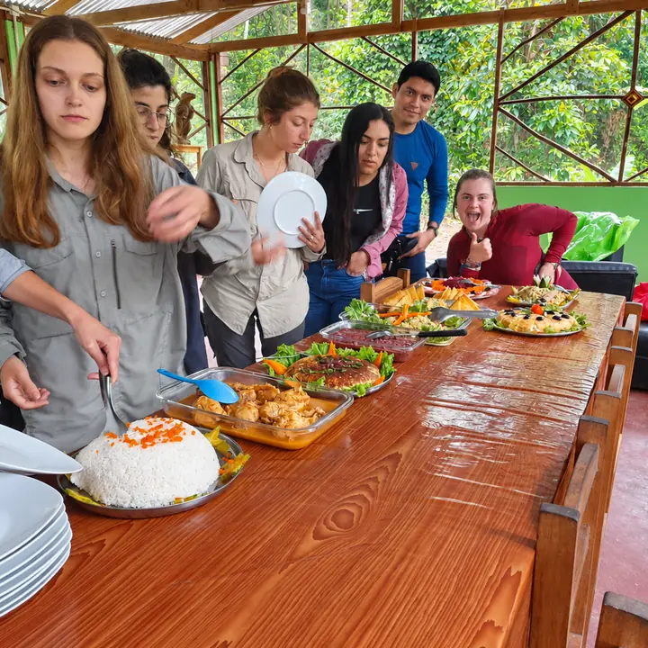 Travelers serving a buffet meal at a rainforest lodge.