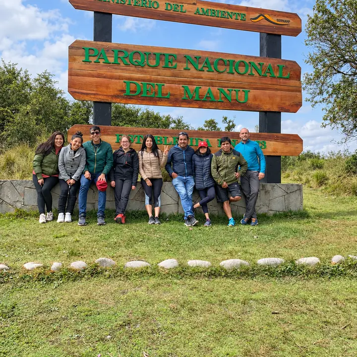 Travel group posing at the Manu National Park entrance sign.