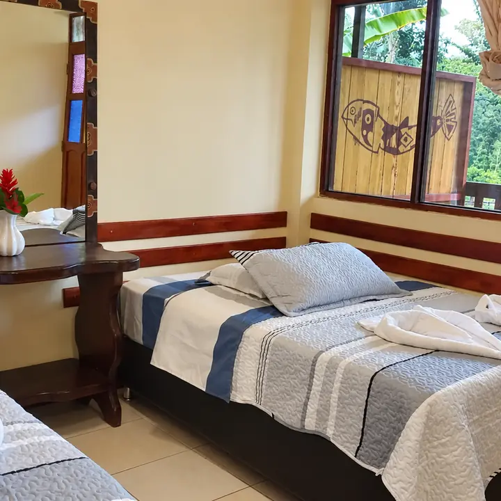 Comfortable bedroom inside a lodge surrounded by rainforest.