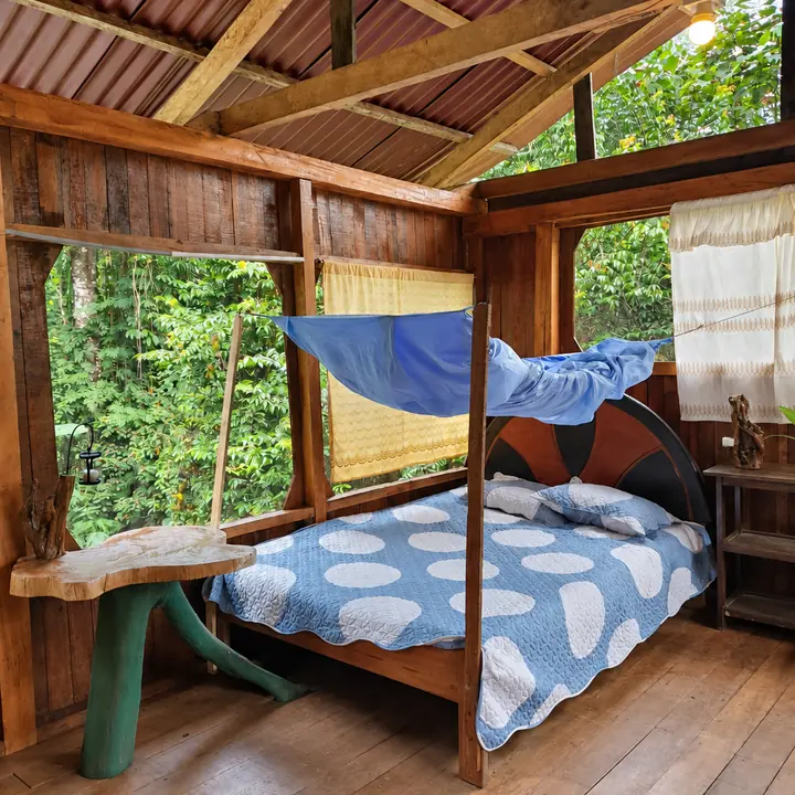 Screened wooden bedroom with rainforest views in Manu.