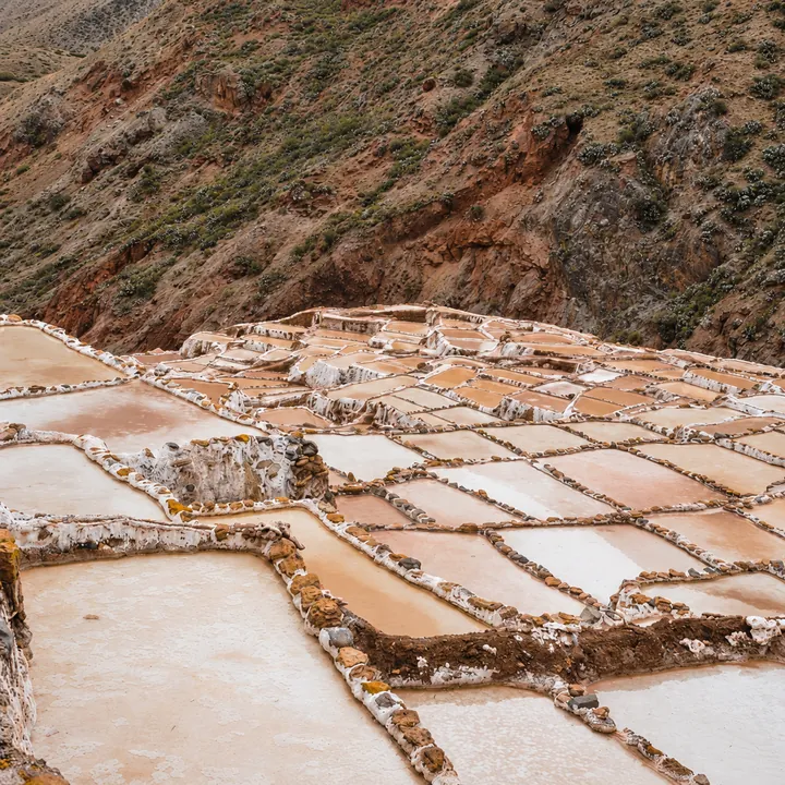 White and pink salt ponds beneath a hillside in Maras.