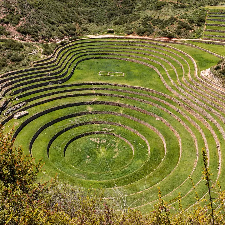 Curved Inca terraces with stone walls and green fields at Moray.