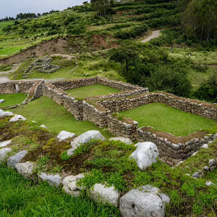 Stone enclosures and green terraces at Puka Pukara near Cusco, Peru.
