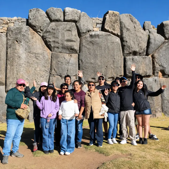 Travel group posing beneath the massive Inca stone walls of Sacsayhuaman.