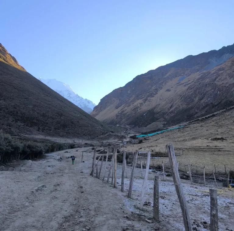 Frost-covered trail and wooden fence during an early morning in the Salkantay mountain valley.